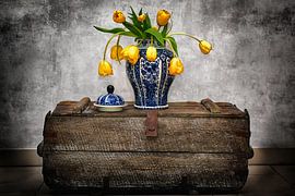Vase bleu de Delft avec tulipes jaunes sur coffre vintage II sur Marlika Art
