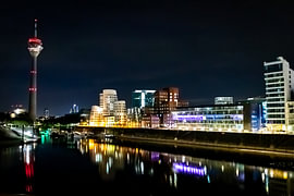Medienhafen Düsseldorf bei Nacht mit Gehry-Bauten, Rheinturm und beleuchtetem Hafenbecken / Marina von Your Happy Life