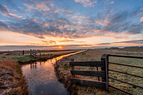 Belle photo de paysage d'une prairie et d'un fossé gelés au lever du soleil.