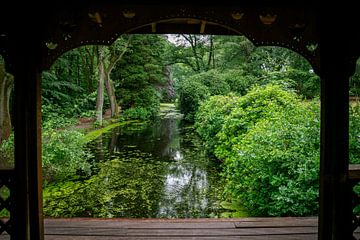 Blick durch eine hölzerne Pergola auf einen von Bäumen mit rotem und grünem Laub gesäumten Teich von ChrisWillemsen