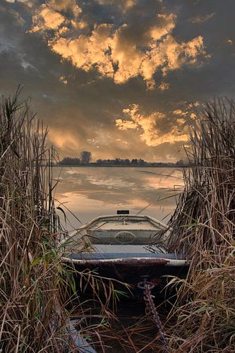 Sunset on a lake with boat in the reeds