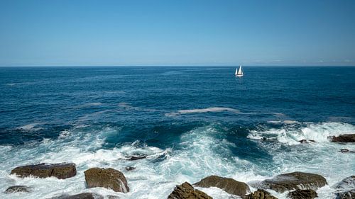 Zee met golven en een zeilboot voor de kust van San Sebastian van Rick Van der Poorten