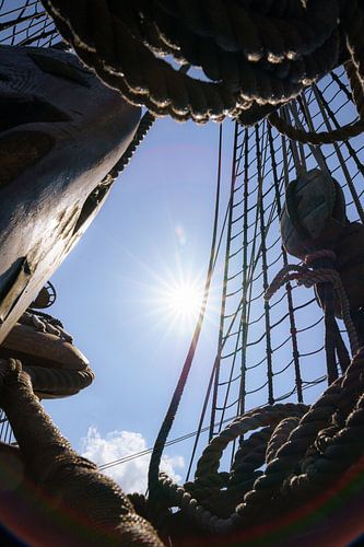 Mast and ropes of old wooden VOC sailing ship against sunlight