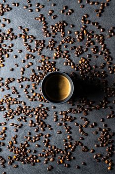 Cup of coffee surrounded by coffee beans