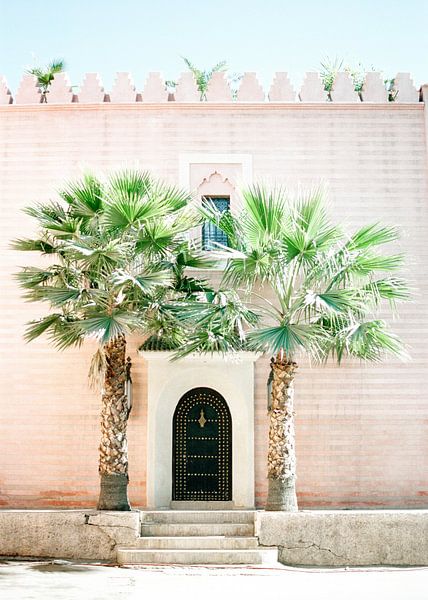 Médina ou Marrakech Magie Maroc Bâtiment rose avec des palmiers en face de celui-ci par Raisa Zwart
