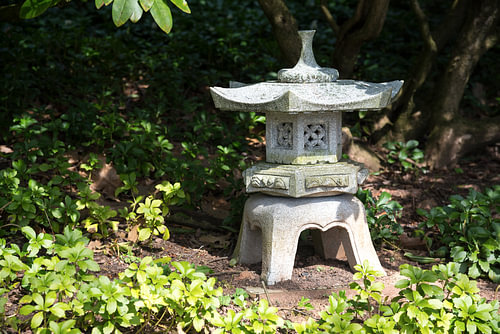 Steinlaterne im Schatten zwischen immergrünen Bodendeckerpflanzen Pachysandra, Gartenlandschaftsgest