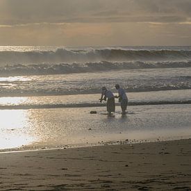 Priester legen während einer Zeremonie auf Bali Opfergaben ins Meer von Minimalistic Travel Photography by.Rieneke