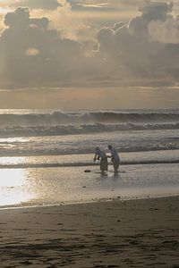 Priester legen während einer Zeremonie auf Bali Opfergaben ins Meer