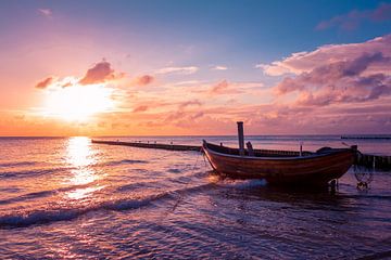 Wooden fishing boat on the beach at dusk by Michel Lask