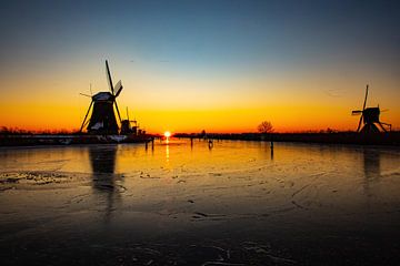 Kinderdijk in winter met schaatsers en zonsopkomst