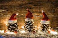 Grappige kerstversiering met dennenappels versierd met rode kerstmutsen, ballen en glimmend licht