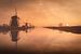 Molens in een mistige zonsopkomst bij Kinderdijk, Nederland van Michael Kuijl