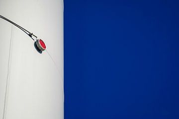 Rood licht van windturbine tegen een blauwe lucht van Sven Van Santvliet