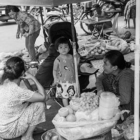 Kind schließt sich Mutter an, die auf der Straße Lebensmittel verkauft von Bart van Lier