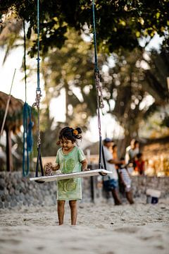 Child plays with sand in fishing village by Yvette Baur