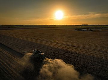 Combine oogst tarwe tijdens een zomerse zonsondergang van Sjoerd van der Wal
