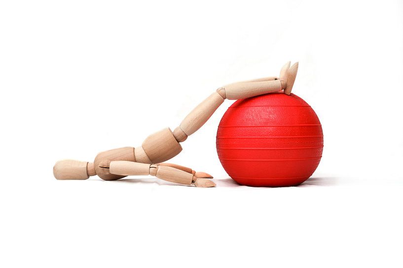 Houten pop doet een fysiotherapeutische oefening op een gymbal van Michar Peppenster