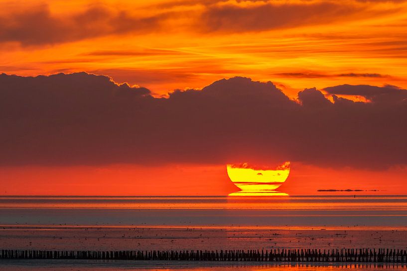 Behind the posts - the sun sinks into the sea by Karla Leeftink