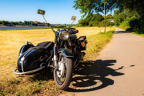 Vintage motorfiets team op een landweggetje bij de rivier