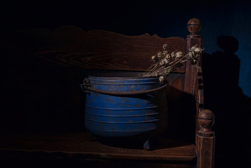Stilleben eines blauen Wasserkessels mit Mohnschoten