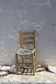 Oude stoel tegen witte muur van Daniël Loman
