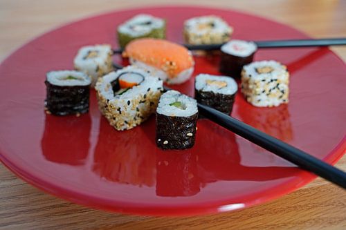 Sushi op een rood bord met eetstokjes