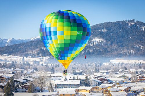 Heteluchtballonnen sieren de lucht boven een besneeuwd Inzell in Duitsland