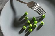 Quelques pois verts et une fourchette avec des ombres sur une assiette grise, un maigre repas de rég par Maren Winter Aperçu