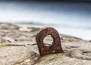 Oud roestig metalen oogje op stenen pier