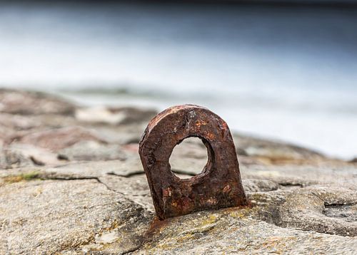 Oud roestig metalen oogje op stenen pier