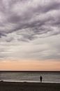 Ein Mensch steht am Strand und genießt nachdenklich die Abendstimmung am Meer von Michael Moser Miniaturansicht