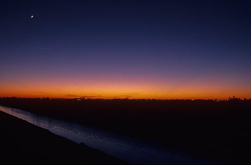 Winter landscape with moon at sunset.