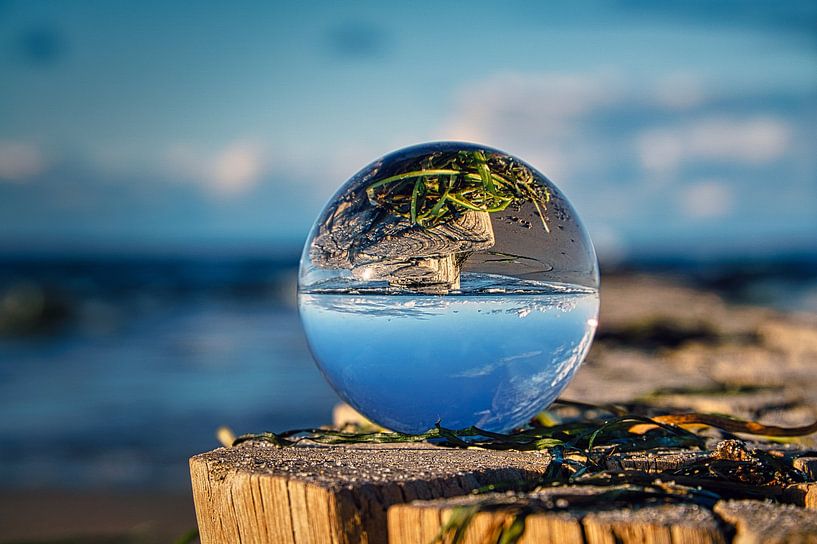 Glass sphere on a groyne at the Baltic Sea. The groyne is reflected in the sphere. by Martin Köbsch