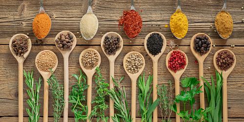 Kleurrijke verscheidenheid aan specerijen en verse kruiden op hout