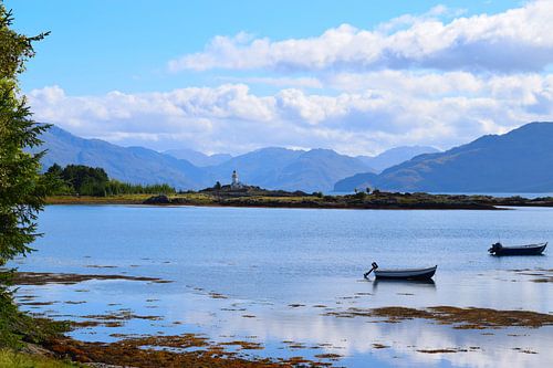 Bateaux de pêche dans un lac avec un phare en arrière-plan