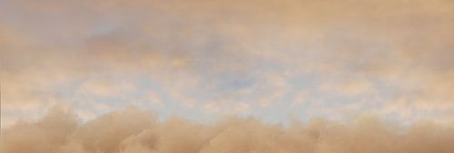 Geel gekleurde lucht met pluizige wolken in een avondlijke lichtstemming