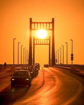 De brug van Krefeld-Uerdingen in symmetrie met de zon. Het warme licht benadrukt de heldere lijnen en creëert een visuele diepte die de precisie van dit moment versterkt. van Lichterkiste
