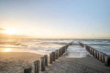 Wellenbrecher am Strand während eines stimmungsvollen Sonnenuntergangs von John van de Gazelle