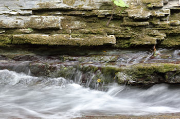 Moosbewachsene Schichten und rauschendes Wasser