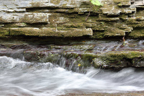 Moosbewachsene Schichten und rauschendes Wasser