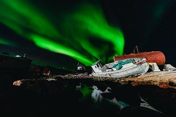 Noorderlicht (Aurora Borealis) boven een scheepswrak en weerspiegelt in het water van Martijn Smeets