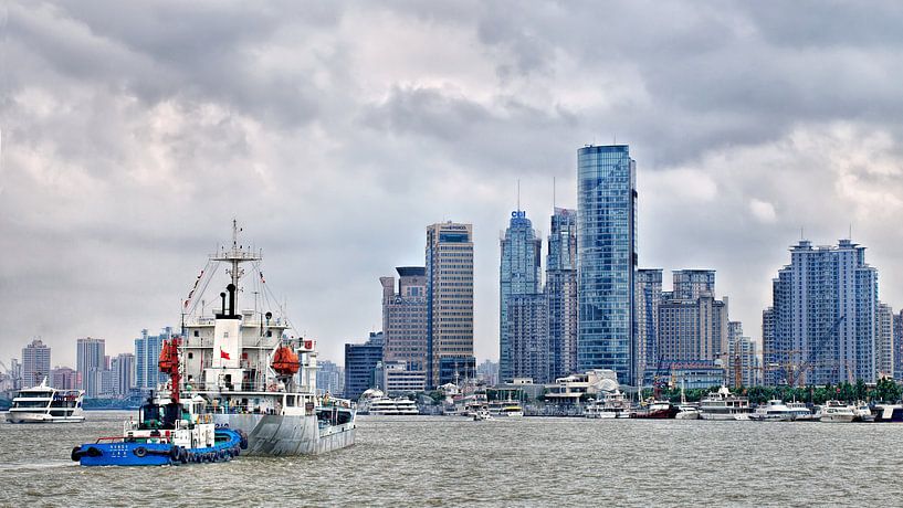 rivier met schepen en de skyline met hoogbouw, Shanghai van Tony Vingerhoets