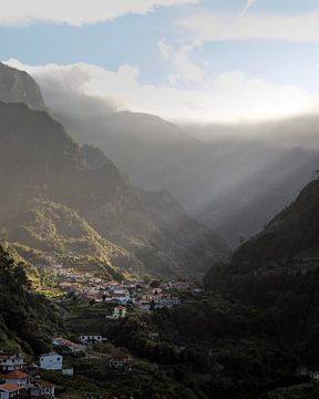 Het licht dat precies op het dorp valt tussen de bergen van Edwin Kooren