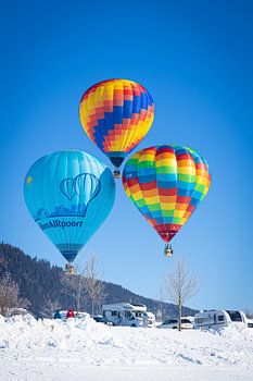 Heißluftballons schmücken den Himmel über dem verschneiten Inzell in Deutschland