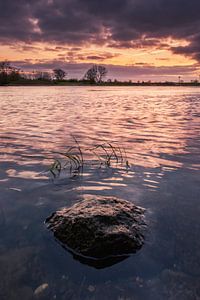 Ein Stein allein im Wasser bei Sonnenuntergang