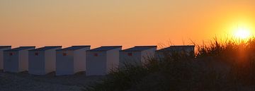 Zonsondergang aan Belgische kust, strandhuisjes en duinen.