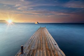 Oude houten steiger aan zee bij zonsondergang