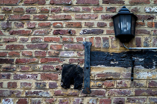A black street lamp against a brick wall