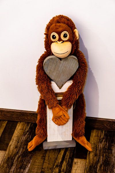 Un singe en tissu suspendu à un cœur de bois par Tom Voelz