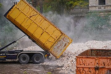Vrachtwagen op een bouwplaats dumpt een container met stenen